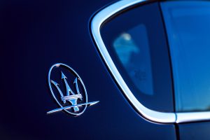 Elegant close-up of the iconic Maserati logo on a luxury vehicle, exuding style and sophistication.