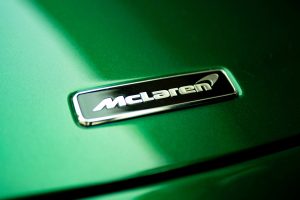 Detailed view of a shiny McLaren logo on a sleek green car surface, highlighting luxury design.