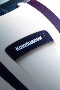 Elegant close-up of a cream-colored Koenigsegg hypercar with carbon fiber trim.